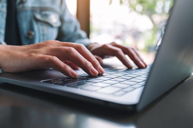 Closeup image of a woman working and typing on laptop computer keyboard