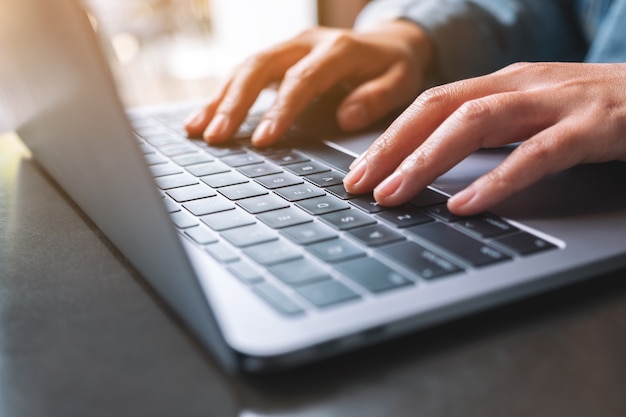 Closeup image of a woman working and typing on laptop computer on the table