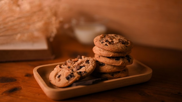 Closeup image A wooden plate of yummy chocolate chip cookies on wooden table background