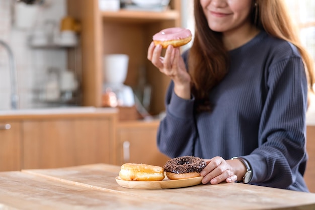 Closeup image of a young woman holding and enjoyed eating donuts at home