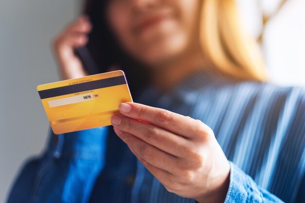 Closeup image of a young woman using credit card for purchasing and shopping online on mobile phone