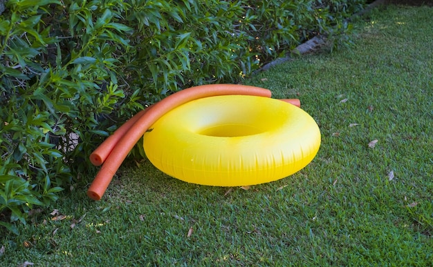 Photo closeup of an inflatable pool ring and pool noodles on the grass in the garden