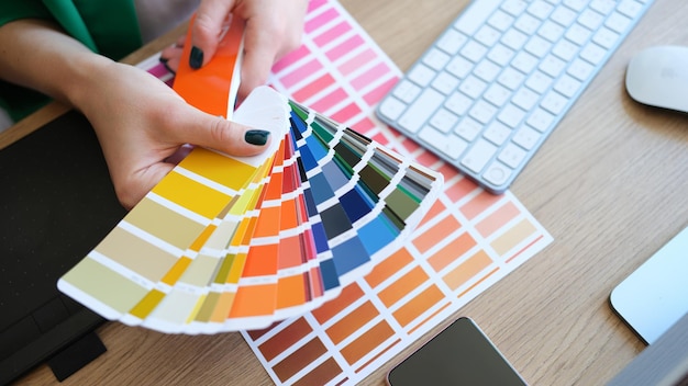 Closeup of interior designer holding fan of multicolored samples woman searching proper colour