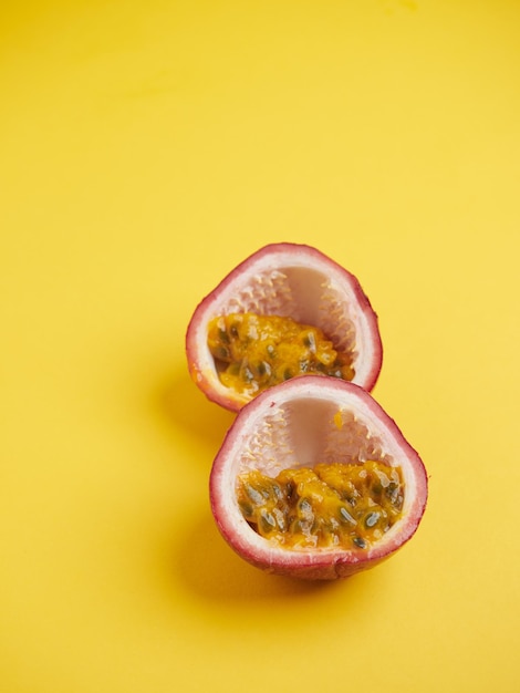 Closeup of the interior of a passion fruit with purple peel and white interior with juicy yellow pulp and seeds On yellow background