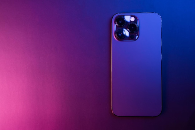 Closeup of iPhone 14 Pro Max Space Black isolated on black background illuminated by blue and pink lights Low light 3 featured cameras Selective focus