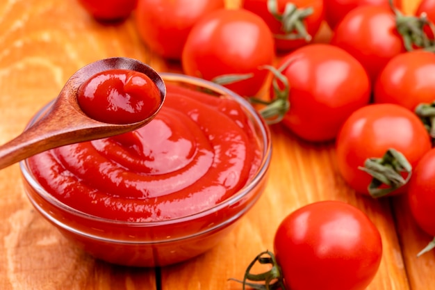 Closeup of ketchup and tomatoes on a wooden background