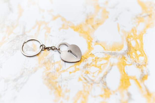 Closeup of keychain in shape of heart lock on marble table