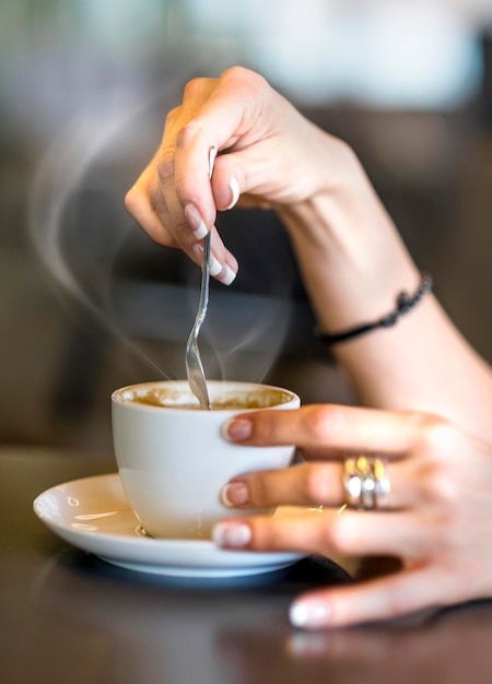 Closeup of lady pouring sugar while preparing hot coffee cup