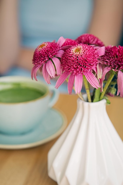 Closeup a large ceramic cup with a green matcha drink on a wooden table