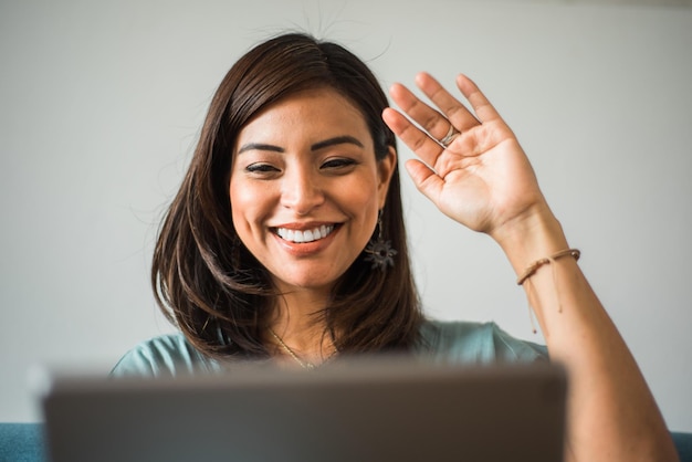 Closeup of Latina teacher greeting her class on a video call at home