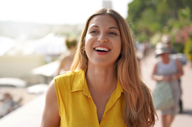 Closeup of laughing woman with yellow shirt walking on Cannes promenade France