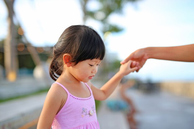 Closeup of little child girl and mother hand in hand.