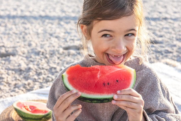 Closeup little girl eats watermelon on the beach