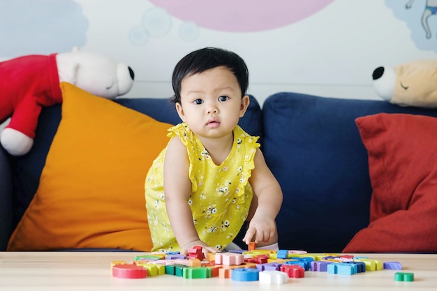 Closeup little girl play wooden jigsaw puzzle toy on sofa in the living room background