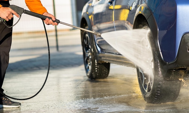 Closeup of male driver washing his car with contactless high pressure water jet in self service car wash.