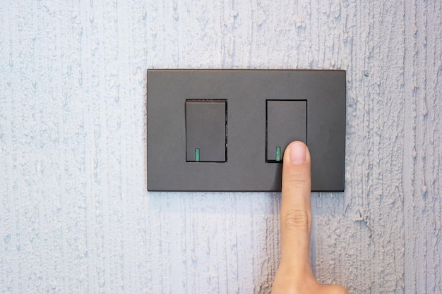 Closeup Male finger is turn on or off on light switch on wall at home Energy Saving power electrical and lifestyle concepts