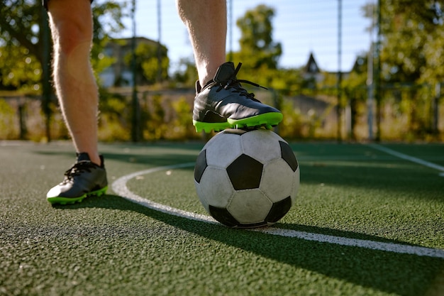 Closeup male foot in boots on soccer ball over green grass field background Outdoor sport activity for adults