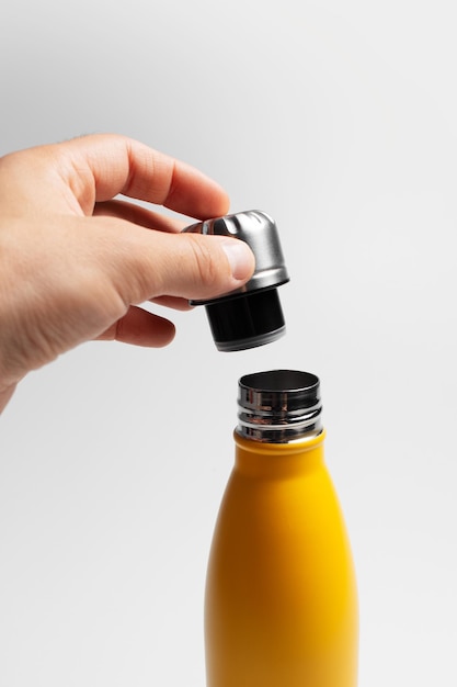 Closeup of male hand holding lid of reusable water bottle on white background