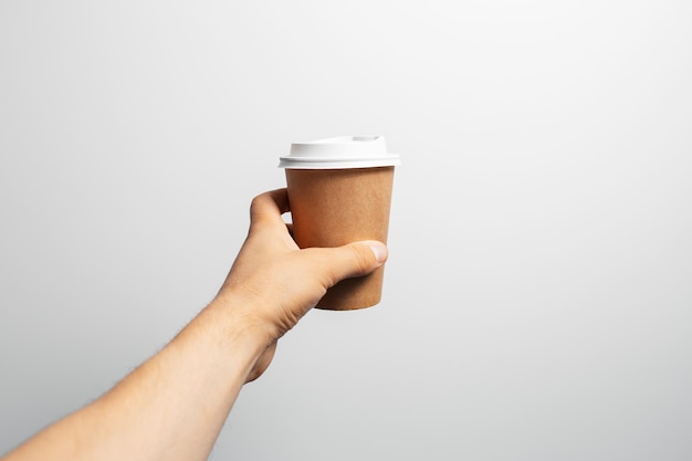 Closeup of male hand holding paper cup of coffee takeaway on white background