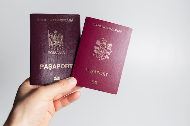 Closeup of male hand holding Romanian and Moldavian passports in hand on white background