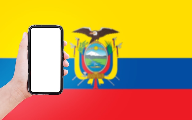 Closeup of male hand holding smartphone with blank on screen on background of blurred flag of Ecuador