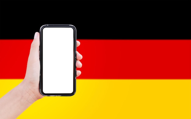 Closeup of male hand holding smartphone with blank on screen on background of blurred flag of Germany