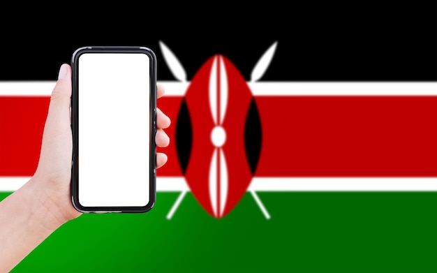 Closeup of male hand holding smartphone with blank on screen on background of blurred flag of Kenya