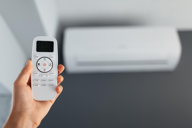 Closeup of male hand using remote control of the air conditioner