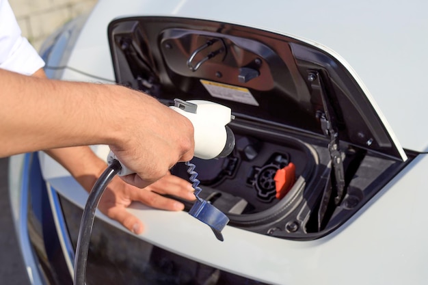 Closeup of male hands connect an electric car to a charger