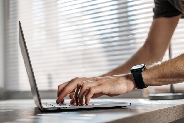 Closeup of male hands on the laptop keyboard typing password programming