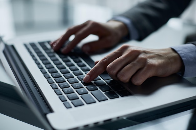 Closeup of male hands using laptop at office