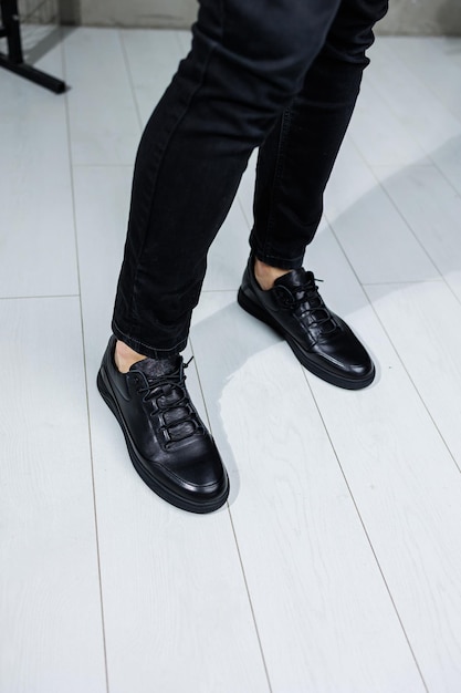 Closeup of male legs in black leather casual sneakers Comfortable men's demiseason shoes