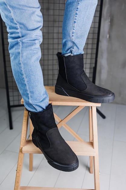 Closeup of male legs in jeans and black winter boots Men's winter warm leather shoes