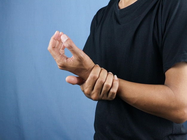 Closeup Man checking pulse on wrist against blue background healthcare concept