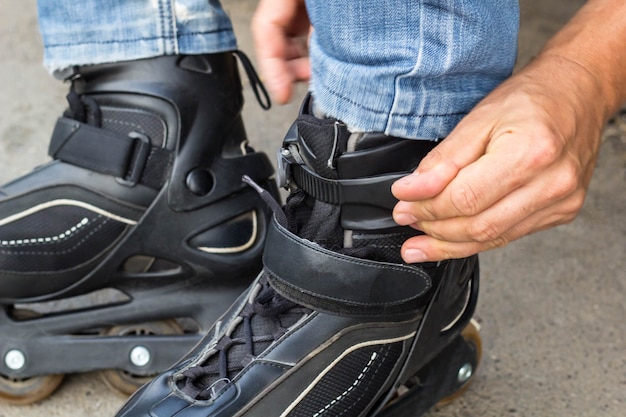 Closeup of man guy putting on roller skates outdoor