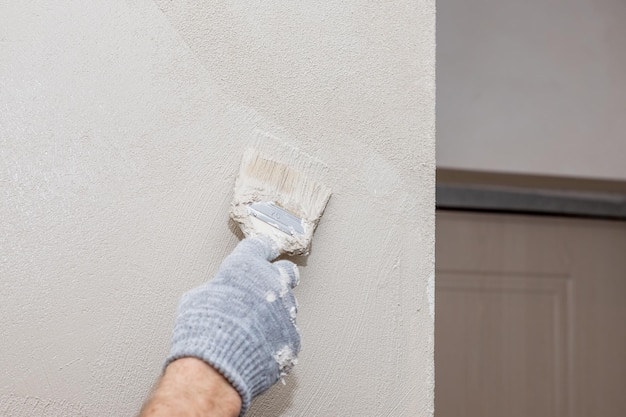 Closeup man hand in glove with paintbrush painting wall creative design house renovation theme restoration and painting of the wallPainting apartment