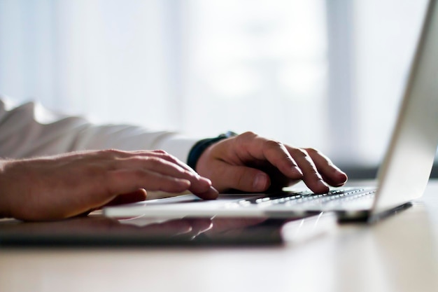 Closeup of man hands typing on a laptop working concept