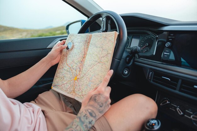 Closeup of a man holding a compass and map inside a car