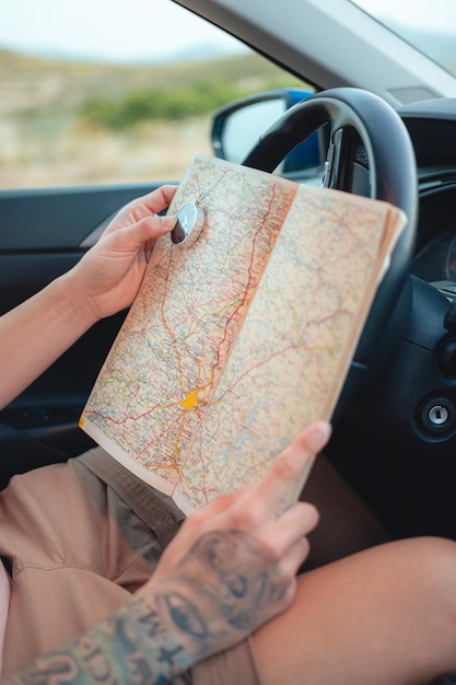 Closeup of a man holding a compass and map inside a car