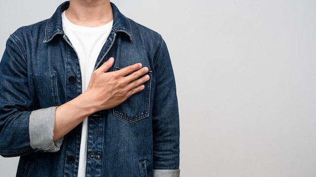 Closeup man jeans shirt hand at his chest to hope isolated