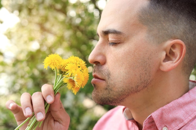 Closeup of a man smelling dandelions in the park