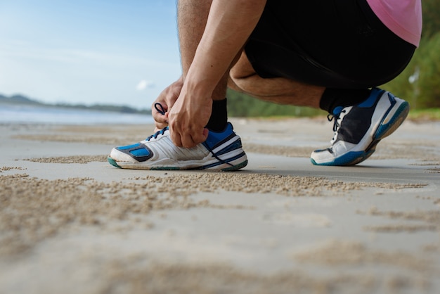 Closeup of man tying shoe laces on the beach