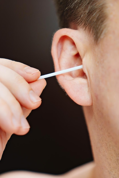 Closeup a man with a cotton swab cleans the ear canals from earwax