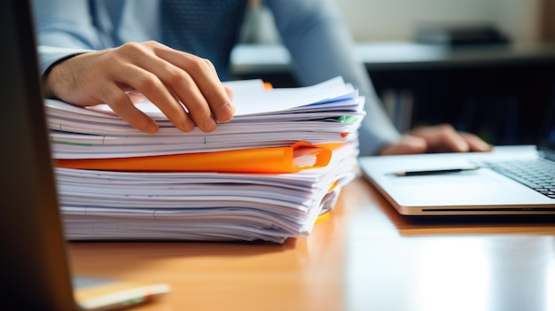 Photo closeup of a man working with a stack of documents and reports on his office desk