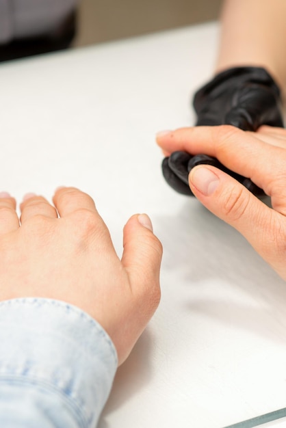 Closeup of manicure master prepares hands of a young woman for manicure procedures.