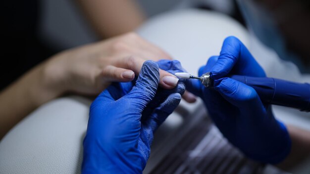 Closeup of manicurist doing manicure to client using special apparatus hardware manicure beauty