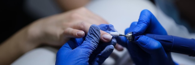 Closeup of manicurist doing manicure to client using special apparatus hardware manicure beauty