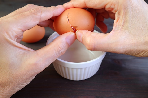 Photo closeup of mans hand cracking an egg into a bowl