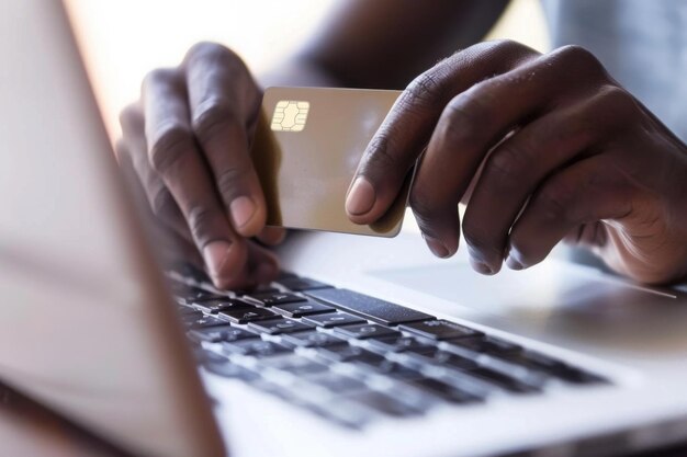 closeup of a mans hand holding a credit card as it makes contact with a laptop highlighting online