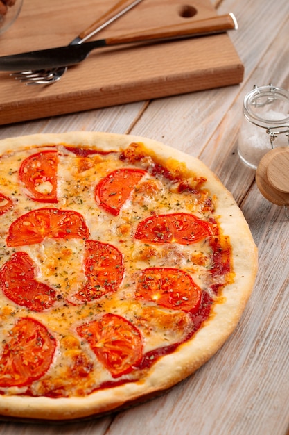 Closeup on margherita pizza with tomatoes on the wooden background